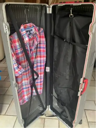 Témoignage client montrant la valise Eliteshell entre-ouverte, avec des vêtements accrochés avec un cintre à gauche, et une housse accrochée à droite contenant de l'équipement sportif.